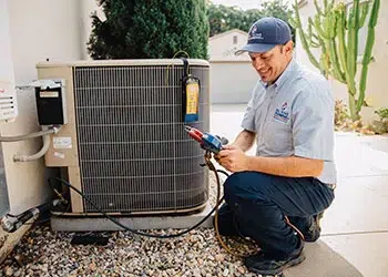 HVAC technician smiling and servicing a system.