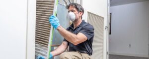 Signs your AC needs repair -- a man inspecting the air filter.